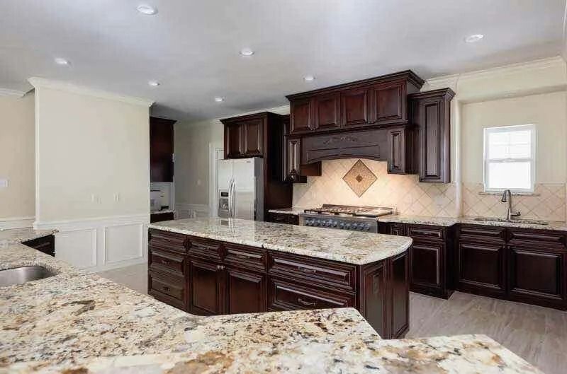 Kitchen with dark wood cabinets, granite countertops, and a large island.
