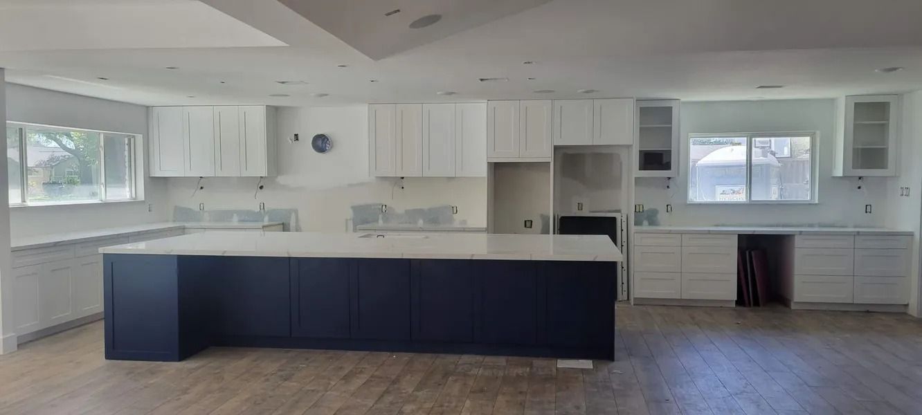 Kitchen with navy blue island, white cabinets, and light countertops.