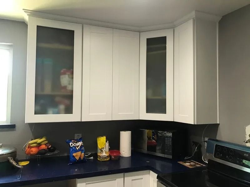White kitchen cabinets above a blue countertop, with a microwave and food items visible.
