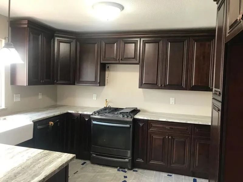 Dark wood kitchen cabinets with a stove and light-colored countertops.
