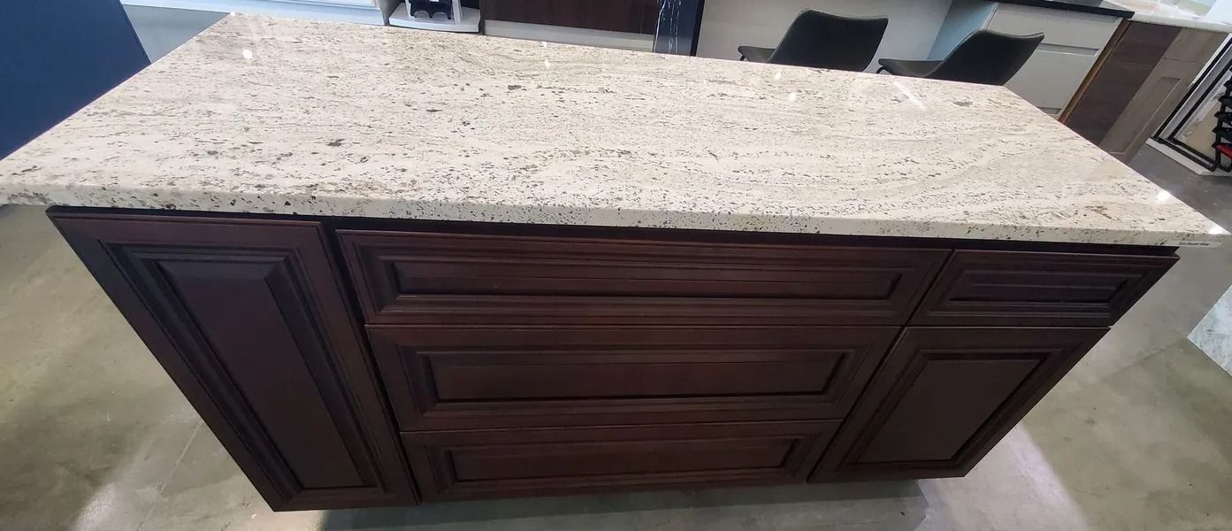 Kitchen island with a light-colored speckled countertop and dark brown cabinets.