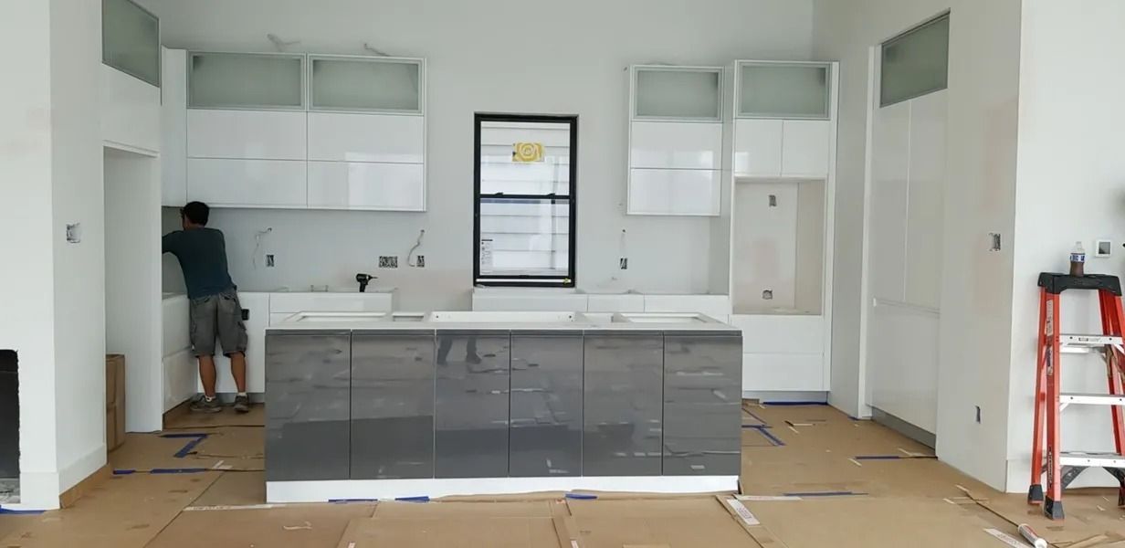 A kitchen under construction with a worker, cabinets, and a central island.