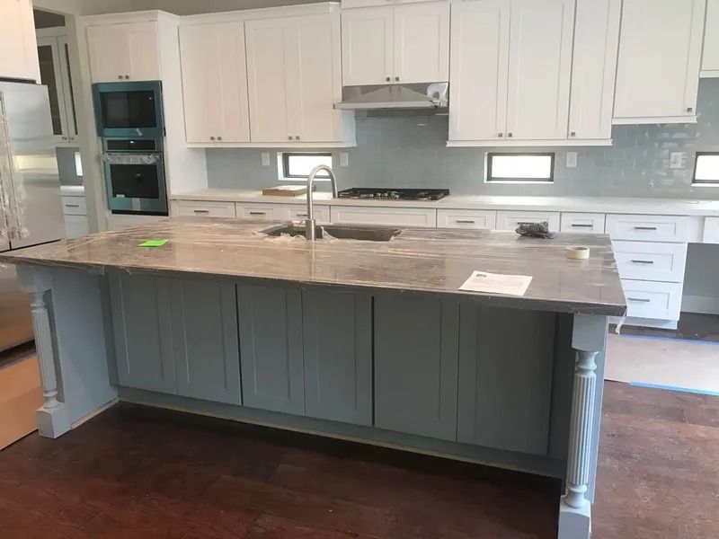 Kitchen with white cabinets, blue island, gray countertop, and stainless steel appliances.
