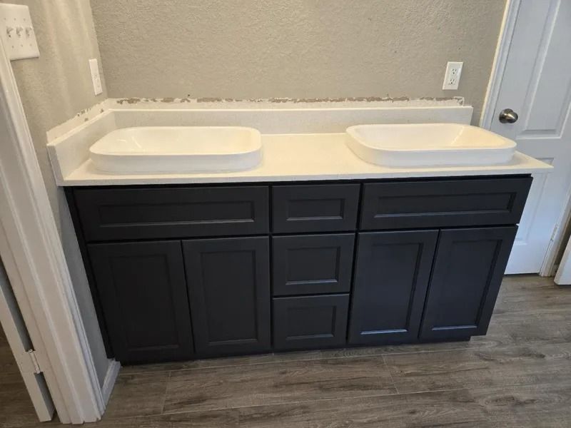 Dark blue double vanity with two white sinks and a white countertop in a bathroom.