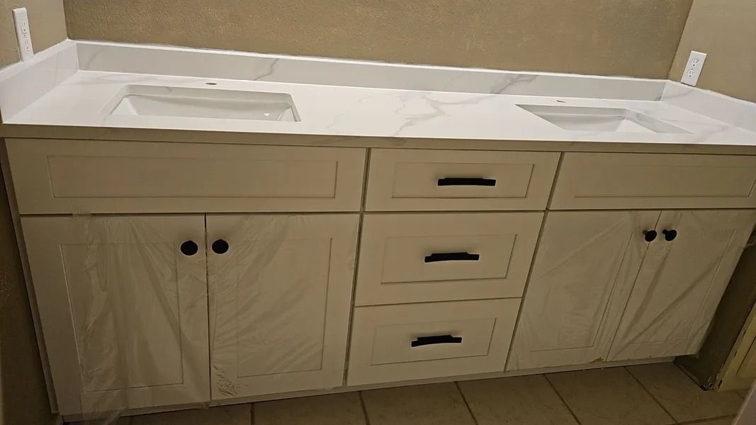 White double vanity with a marble countertop, black hardware, and two sinks.