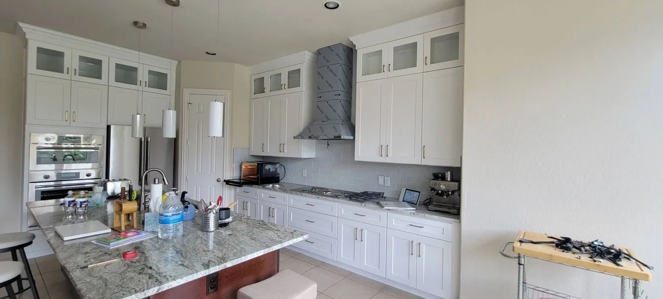 Kitchen with white cabinets, stainless steel appliances, and a granite island.