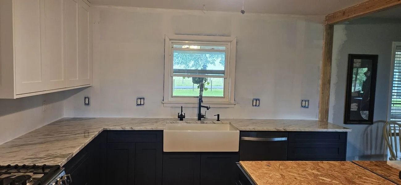 Kitchen with white cabinets, dark blue base cabinets, granite countertops, and a white farmhouse sink.