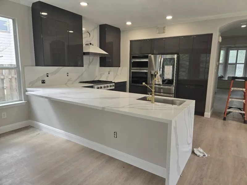 Modern kitchen with gray cabinets, white countertops, and stainless steel appliances.
