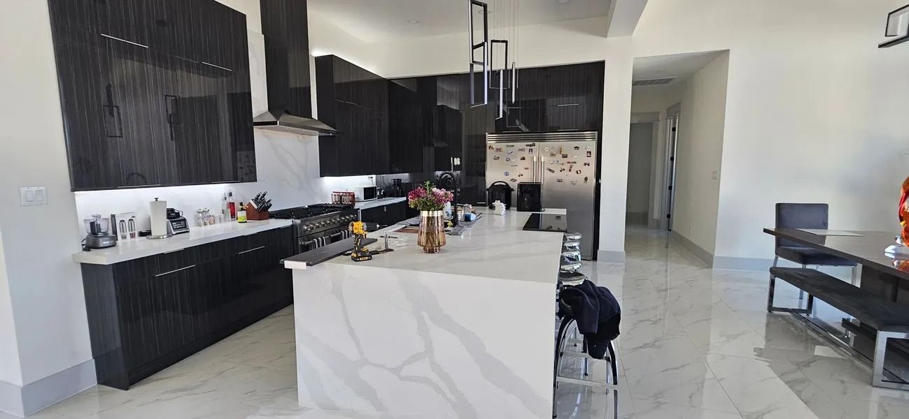 Modern kitchen with dark cabinetry, white countertops, and a large island.