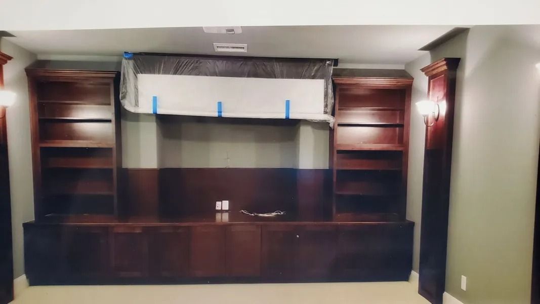 Built-in wooden entertainment center with shelves and cabinets, and a television.