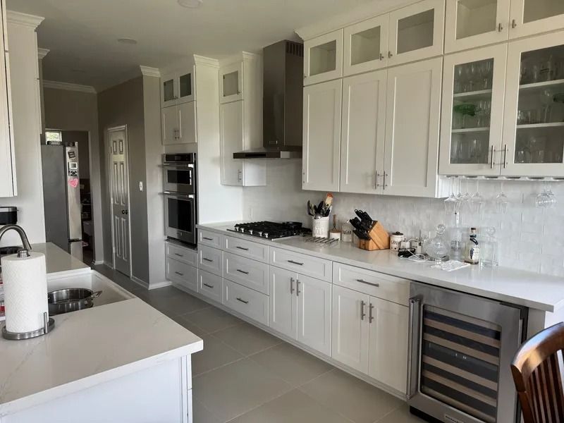White kitchen with light countertops, cabinetry, and stainless steel appliances.