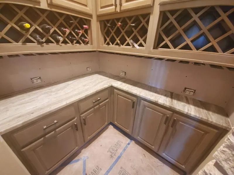 Corner kitchen cabinetry with wine racks, light countertops, and beige cabinets.