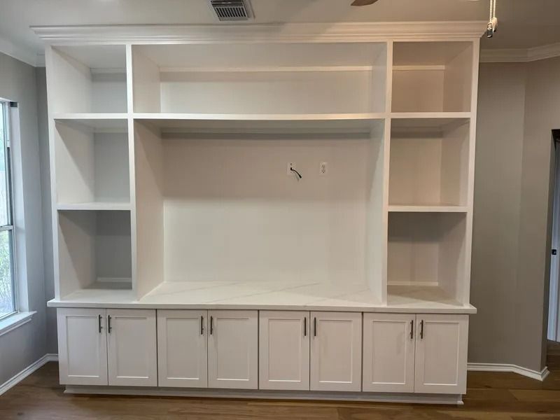 White built-in entertainment center with shelves and cabinets. The center is mounted to the wall.