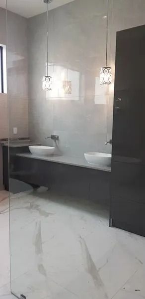 Modern bathroom with two sinks, pendant lights, and marble floors.