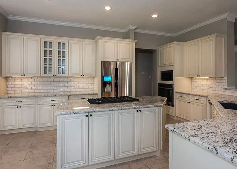 White kitchen with granite countertops, light cabinets, and stainless steel appliances.