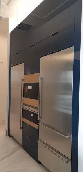 Stainless steel refrigerator and oven built into a dark blue cabinet.