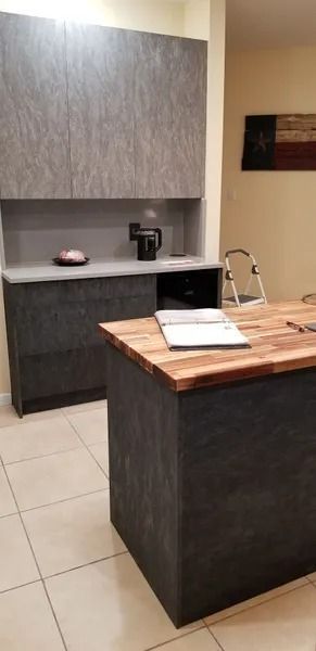 Modern kitchen with dark cabinetry, wood countertop island, and a Texas flag on the wall.
