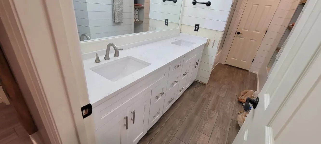 Bathroom interior with a white vanity, a large mirror, and wood-look flooring.