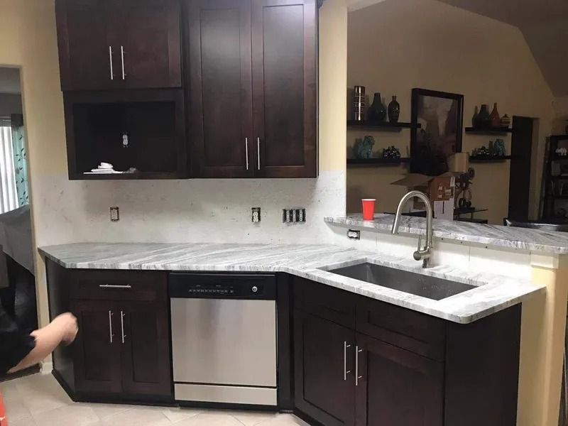 Dark wood kitchen cabinets, stainless steel appliances, granite countertops, and a sink.