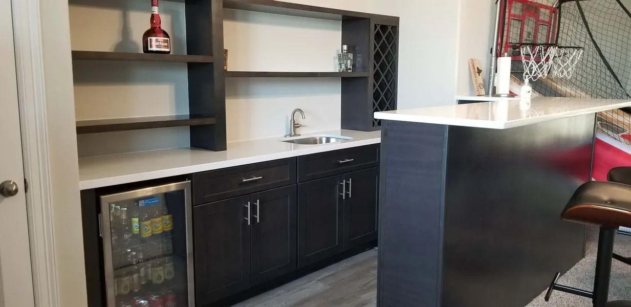Dark wooden bar with white countertop and small refrigerator.