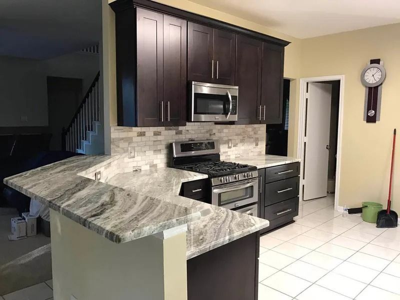 Kitchen with dark cabinets, granite countertops, and a stainless steel range and microwave.