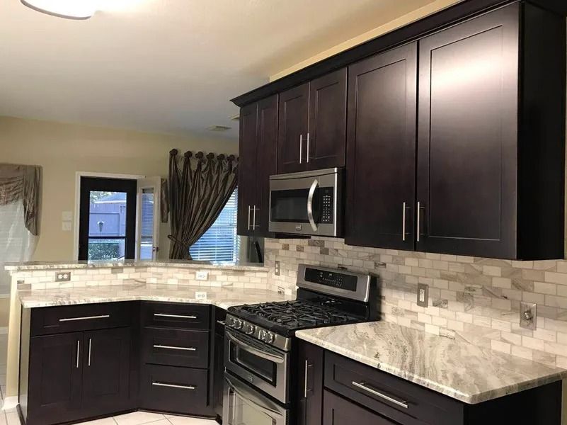 Kitchen with dark brown cabinets, stainless steel appliances, and granite countertops.