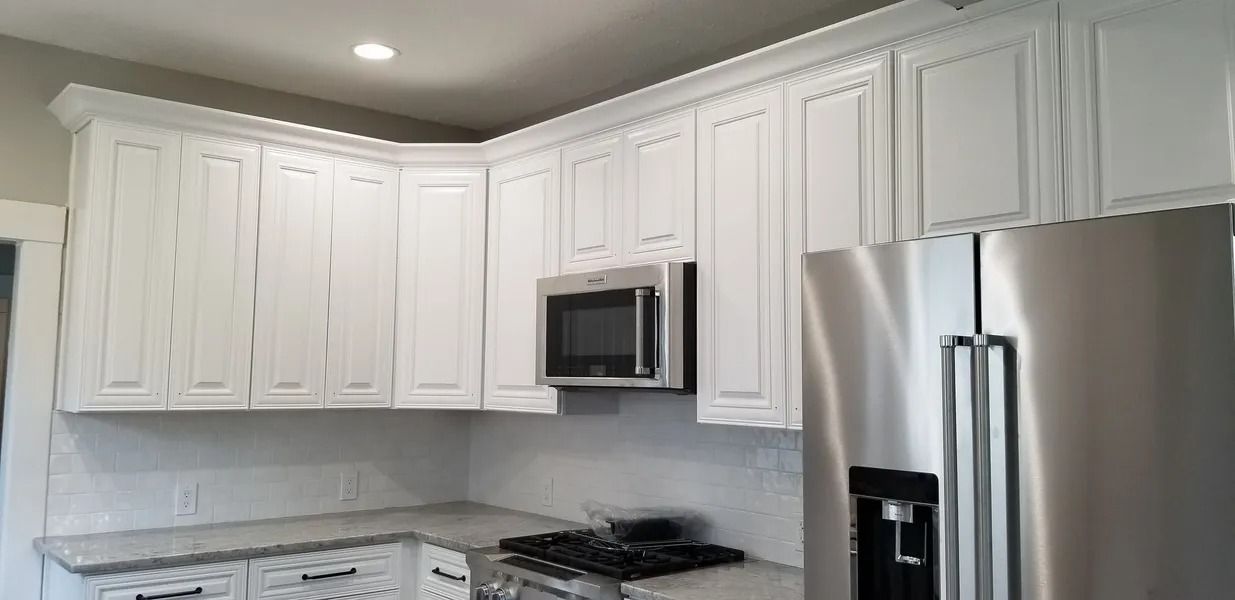 White kitchen cabinets with a stainless steel microwave and refrigerator.