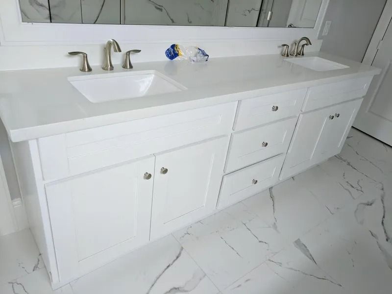 White bathroom vanity with dual sinks, silver faucets, and marble-look floor.