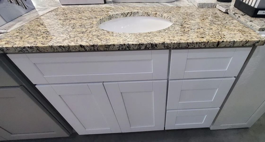 White bathroom vanity with granite countertop and oval sink.
