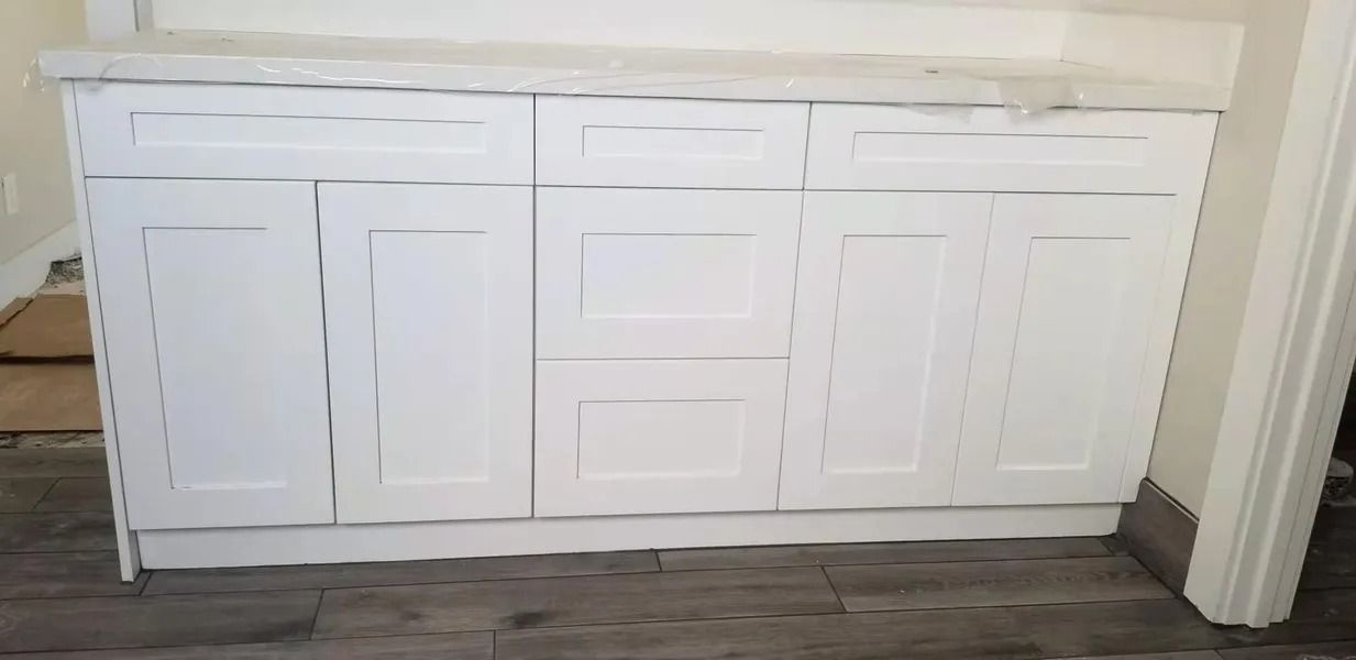 White bathroom vanity with two doors, two drawers, and a countertop.