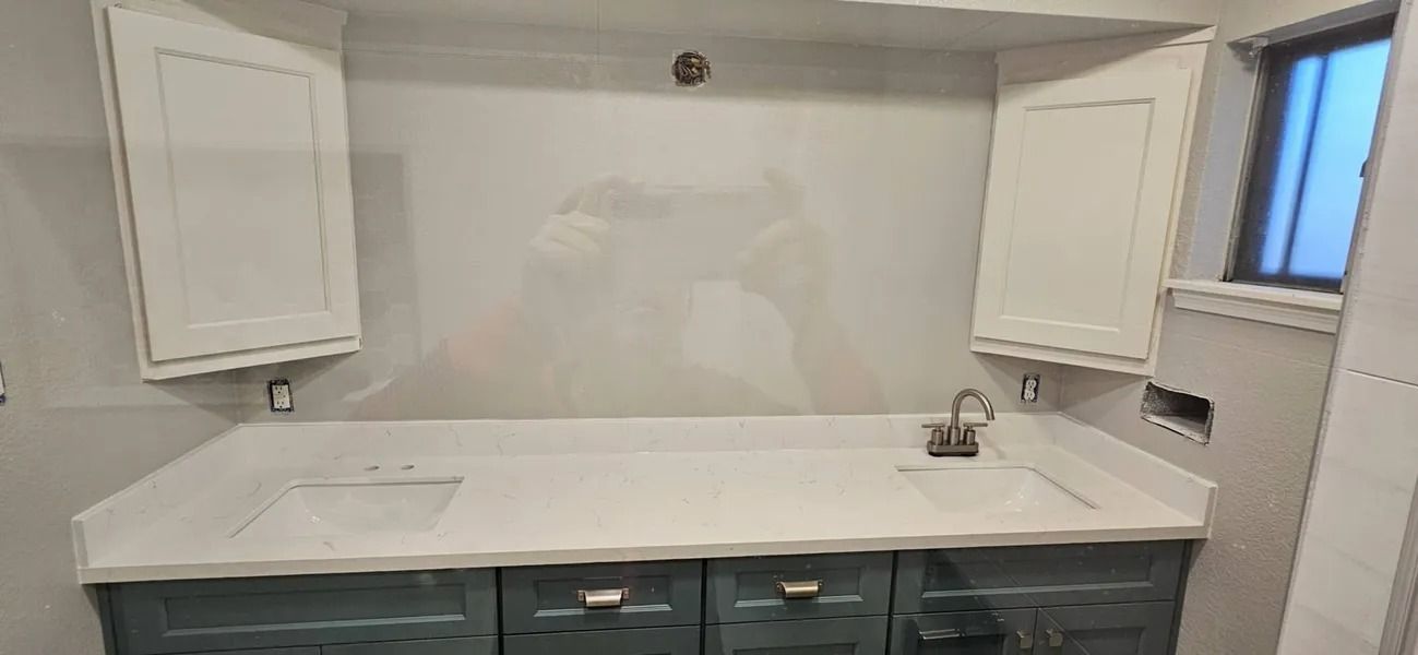 Bathroom with white countertop, blue cabinets, white cabinets, and a window.