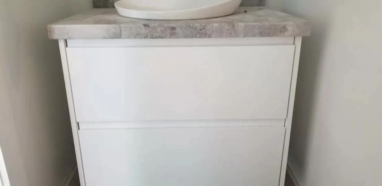 White bathroom cabinet with two drawers and a marble countertop. A white sink sits on top.