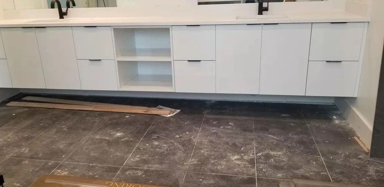 White floating bathroom vanity with a countertop, set against a dark tiled floor.
