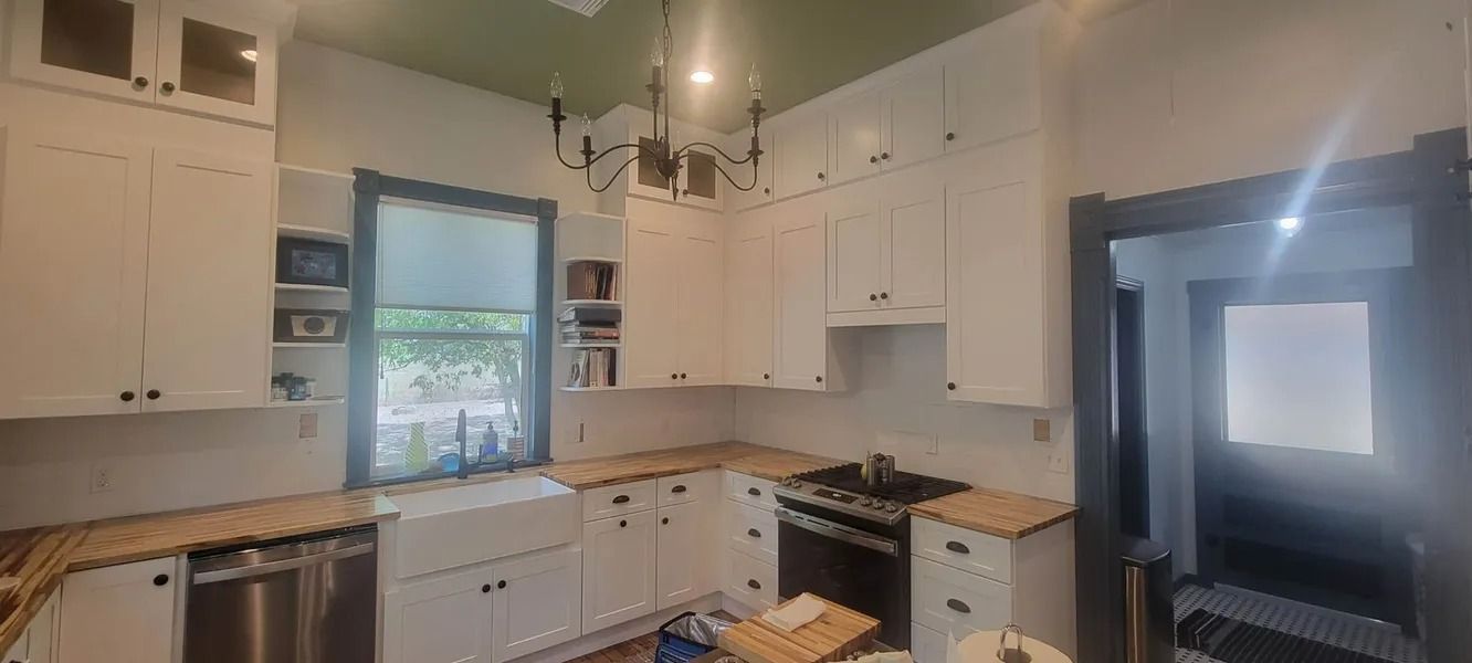 White kitchen with wooden countertops, white cabinets, and a green ceiling.