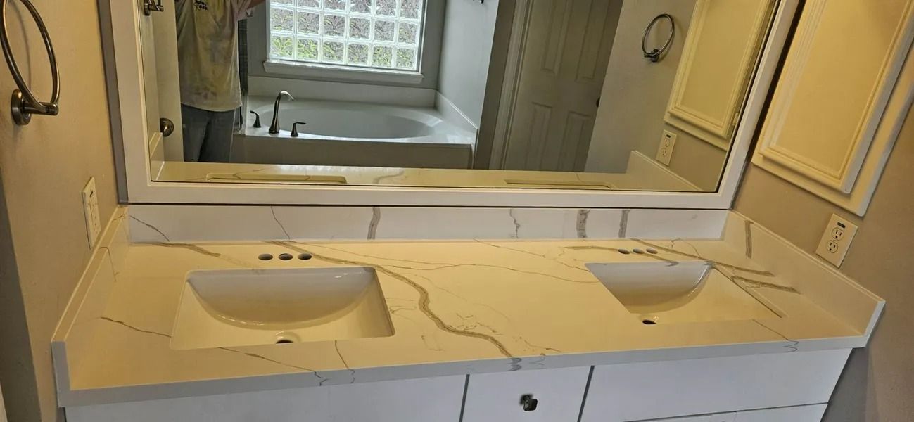 Bathroom vanity with two sinks and a large mirror. Beige countertop with vein-like detailing.