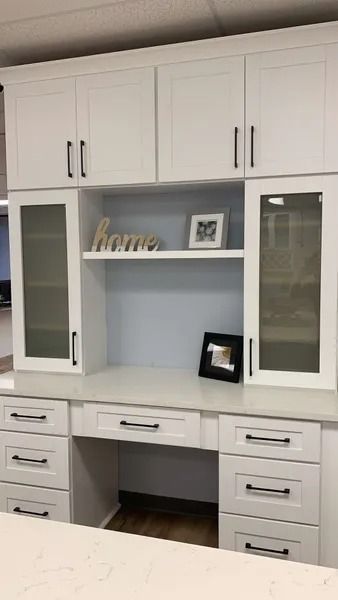 White built-in desk with overhead cabinets, glass-fronted cabinets, and drawers. Features decor: 