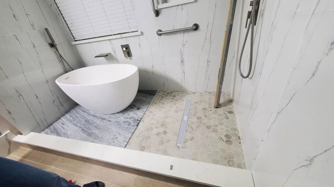 Bathroom with a freestanding oval tub and a walk-in shower. Marble walls and flooring.