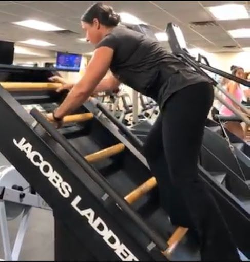 A woman is climbing a jacobs ladder in a gym