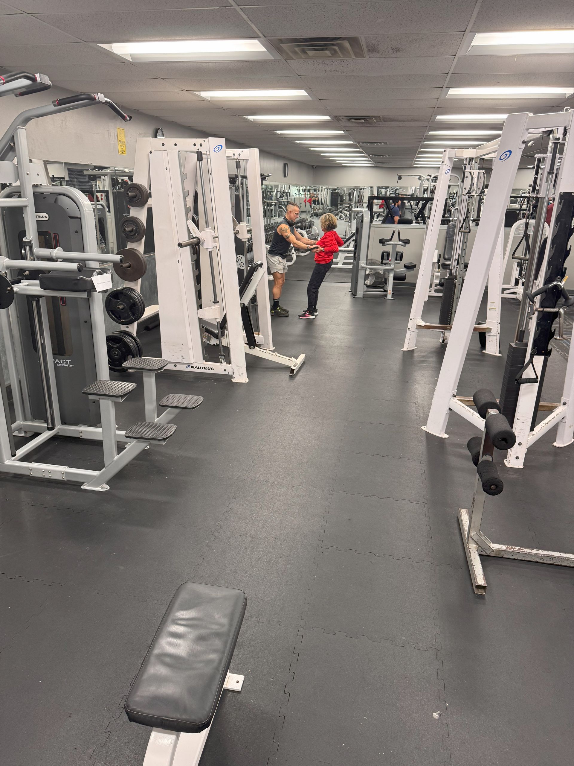 A gym with a lot of equipment and people working out