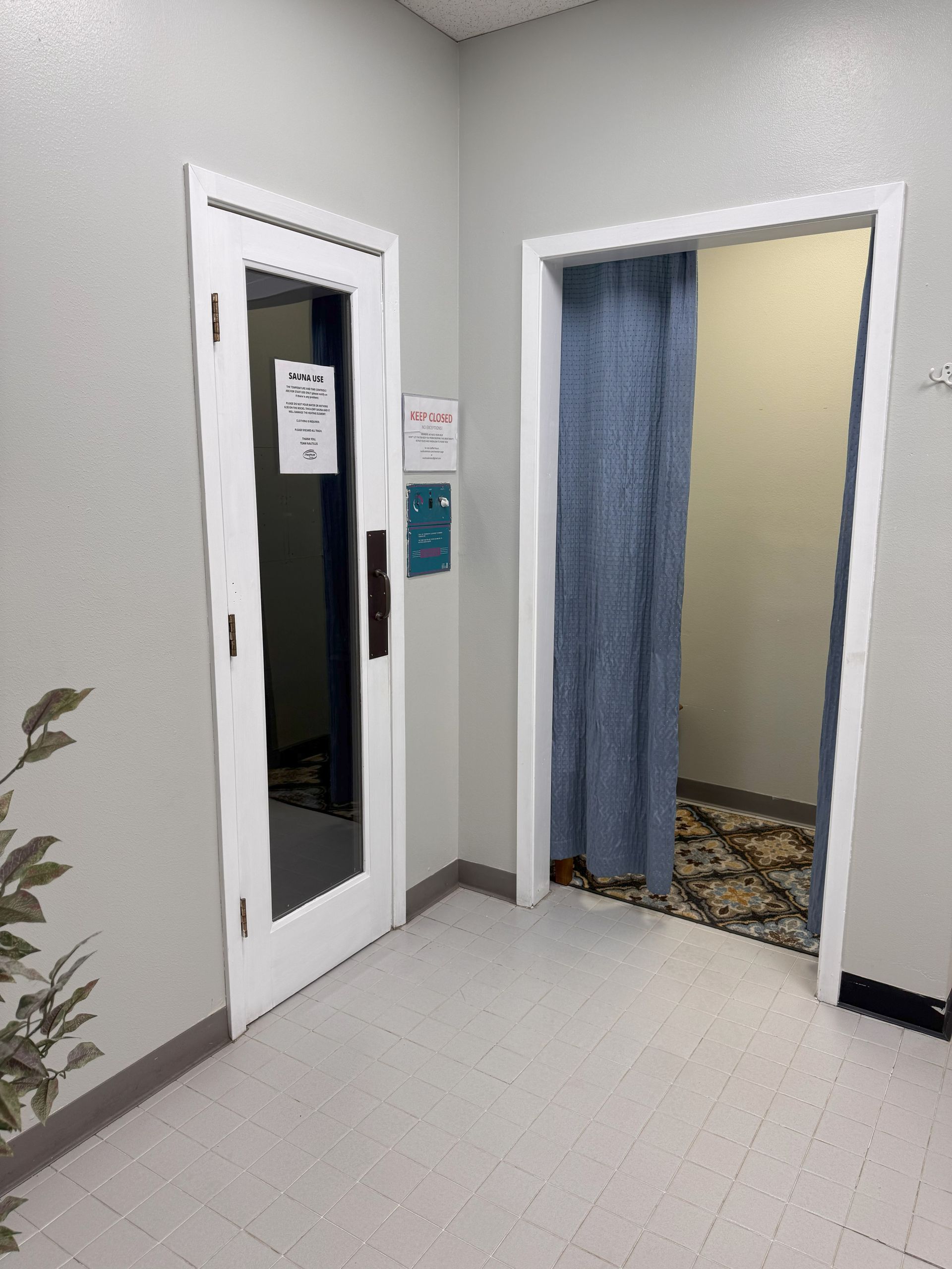 A hallway with two doors leading to a room with a blue curtain