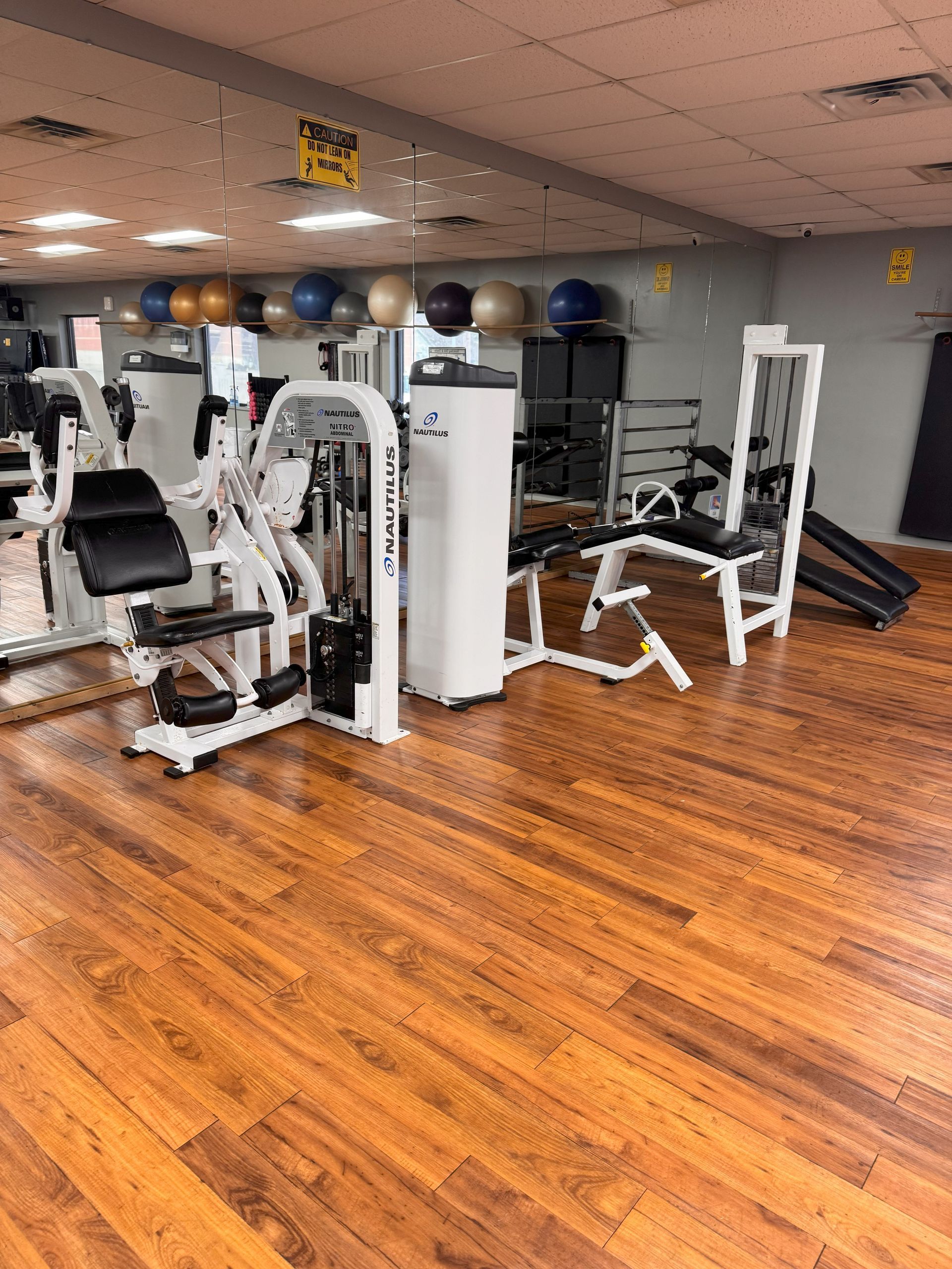 A gym with a lot of exercise equipment and a wooden floor