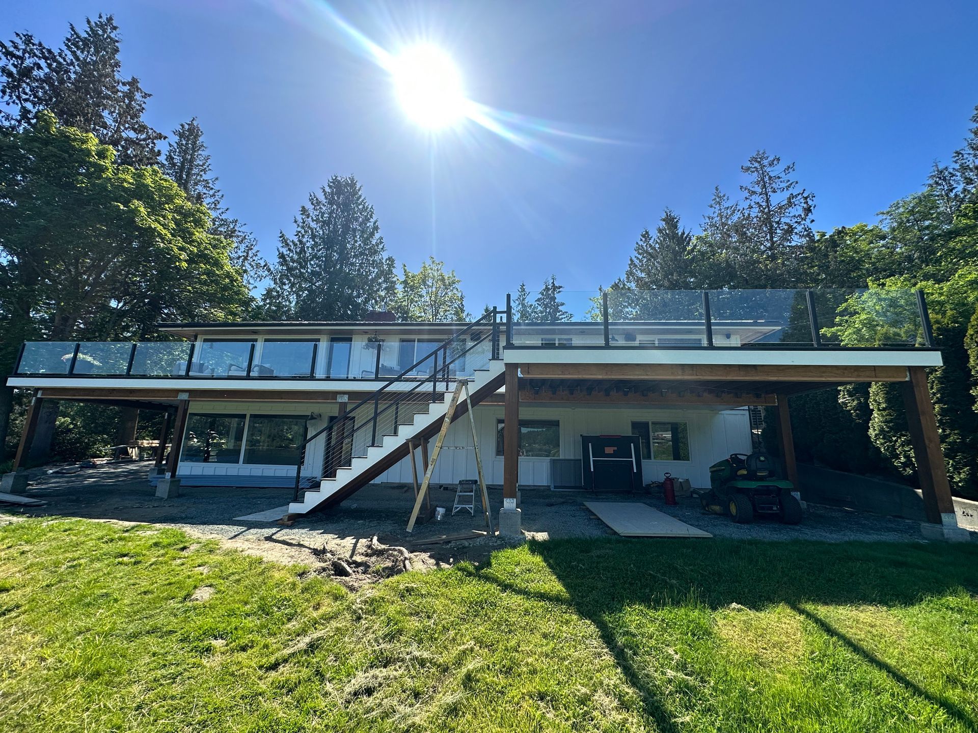 Newly installed deck floor, glass railing, and black stair