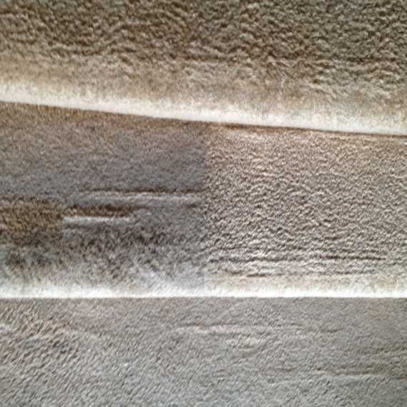 Close-up of a beige, textured fabric surface with horizontal seams and a small dark mark