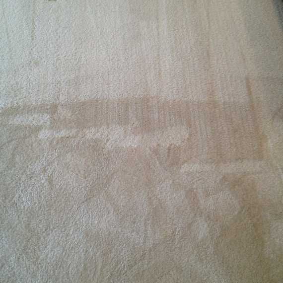 Close-up of a beige fabric with faint, worn rectangular patterns and subtle texture.