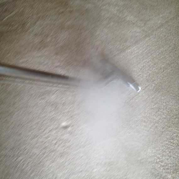 White cleaning cloth or pad on beige carpet, with a dark handle entering from the left.