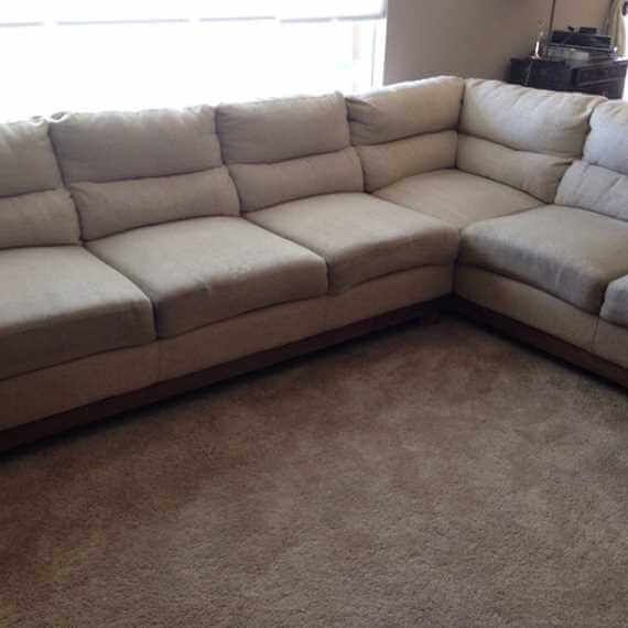 Beige sectional sofa with cushions in a living room on brown carpet.