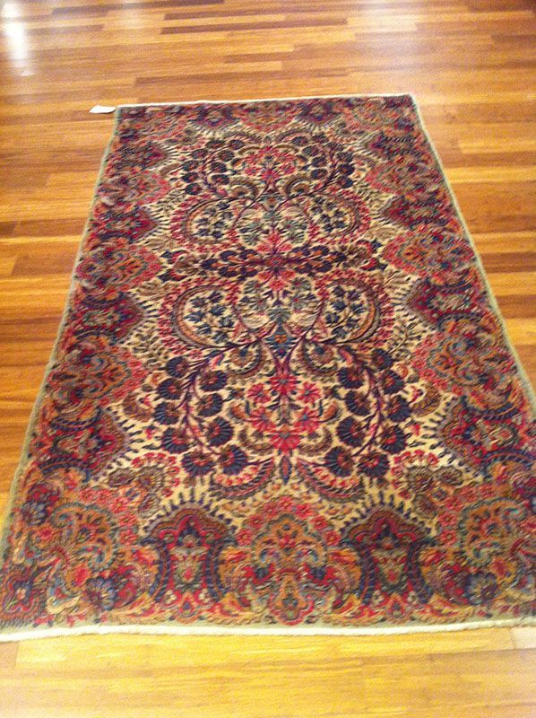 Oriental rug on wooden floor; intricate floral design in red, brown, and beige.