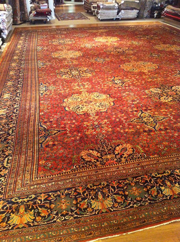 Large, ornate red Persian rug with floral patterns and a dark border on a wooden floor.