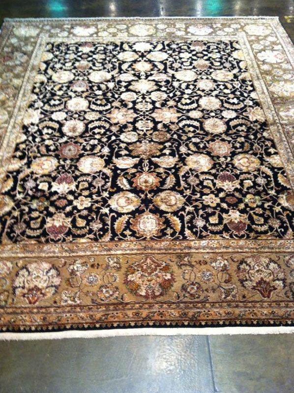 Black and tan ornate Oriental rug with floral design.