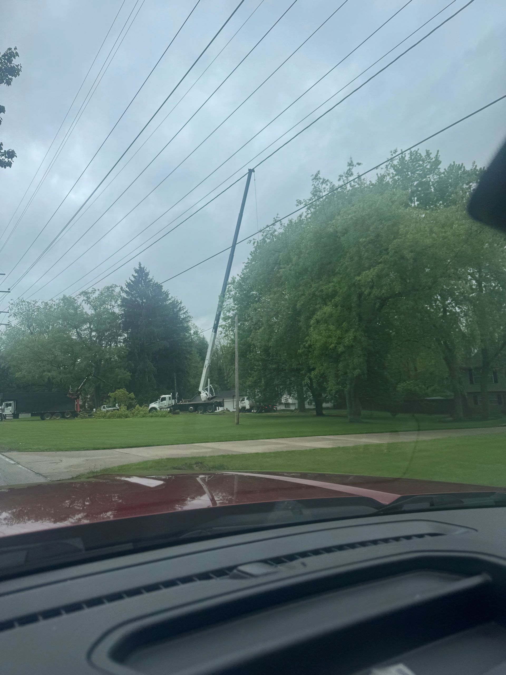 A red truck is driving down a street with a crane in the background.